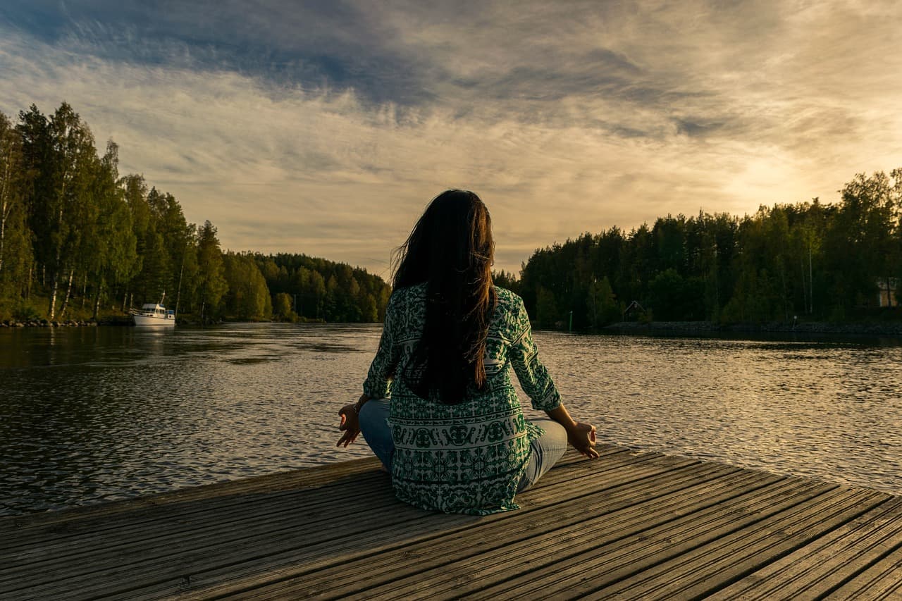 women doing yoga beside lake